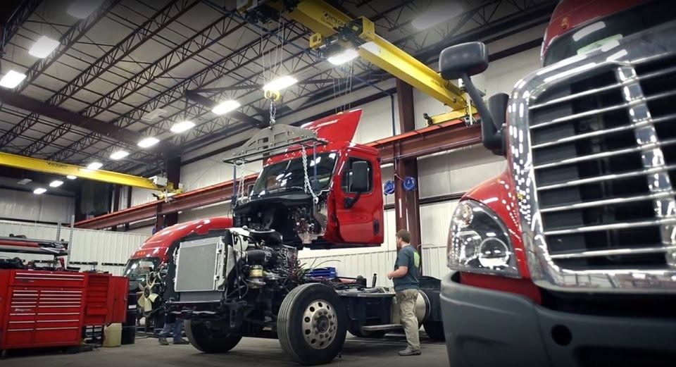 Semi truck cab lifted by overhead crane during repair at Quality Truck And Bus Repair in St Paul, MN